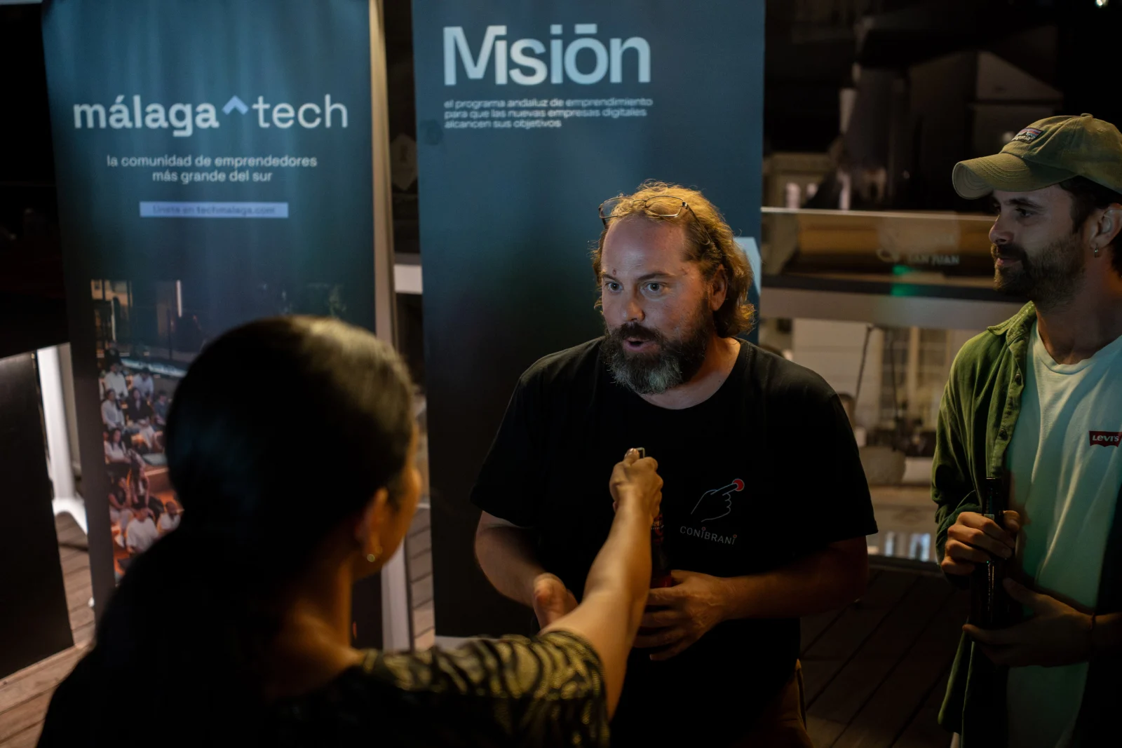 Conversación delante de los roll-ups de Málaga Tech y Misión Andalucía en el Terraceo de octubre